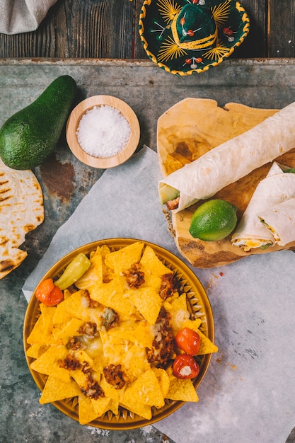 Overhead view of mexican nachos tortilla chips; lemon; avocado on rusty background