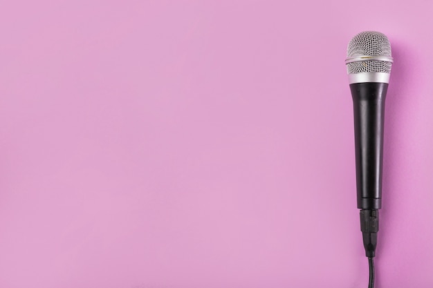 An overhead view of microphone on pink background