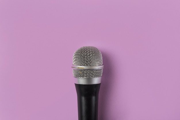 An overhead view of microphone on pink background