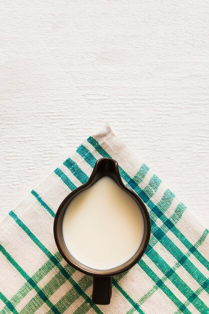 Overhead view of milk in the mug over the cotton napkin