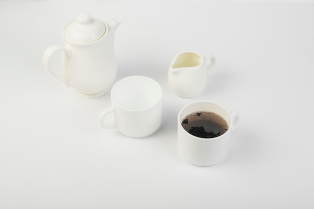 An overhead view of milk; tea and teapot on white background