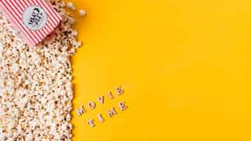 Free photo an overhead view of movie time text near the popcorns against yellow background