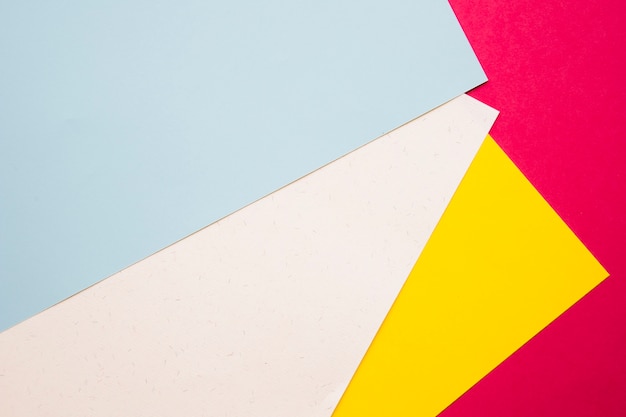 Overhead view of multi colored cardboard papers on pink surface