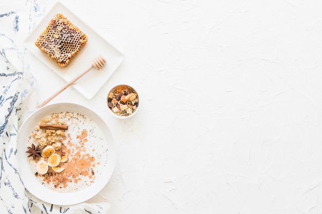 Overhead view of oats healthy breakfast and dryfruits on textured white background