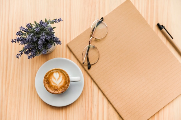 Бесплатное фото Верхний вид кофе латте, канцелярские принадлежности и цветок лаванды на деревянном фоне