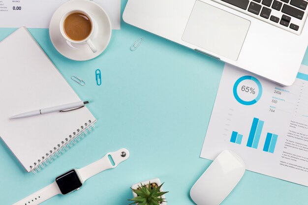 파란색 배경에 문구, 노트북, 마우스 및 스마트 시계와 사무실 책상의 오버 헤드보기