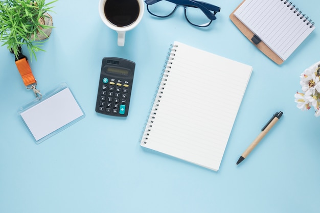 An overhead view of office stationery on blue desk