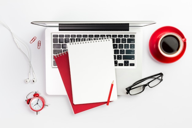 사무 용품, 노트북, 커피 컵, 알람 시계 및 화이트 책상 위에 안경의 오버 헤드보기