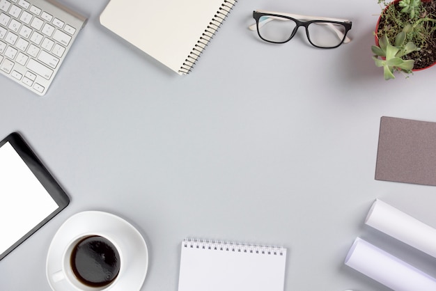 An overhead view of office supplies with coffee cup against gray background