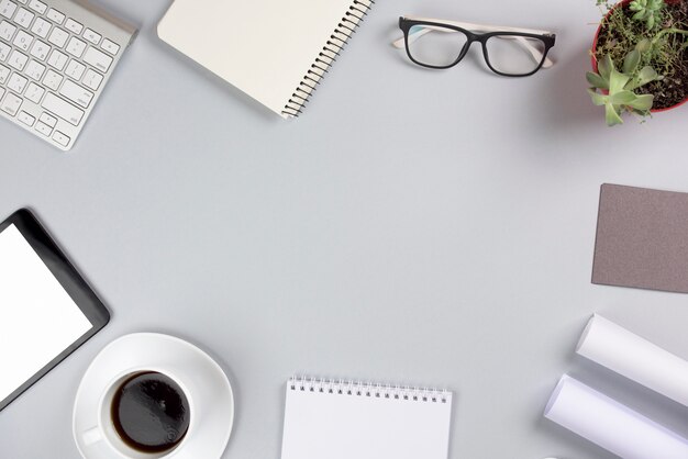 An overhead view of office supplies with coffee cup against gray background