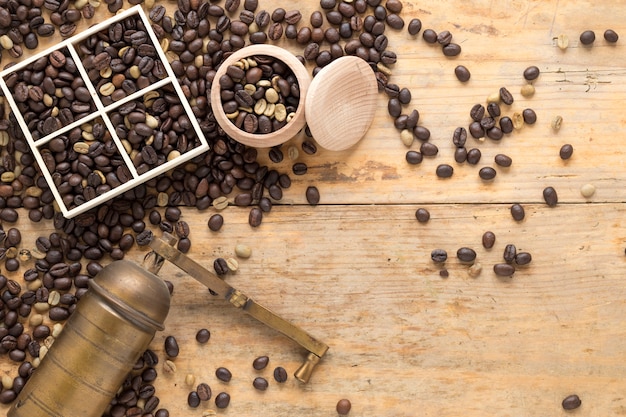 An overhead view of old coffee grinder with coffee beans in container and table