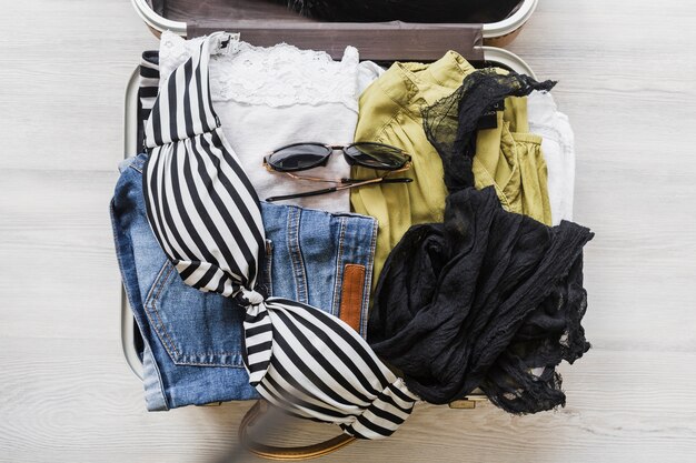 복장 및 액세서리가있는 열린 여행자 가방의 오버 헤드보기