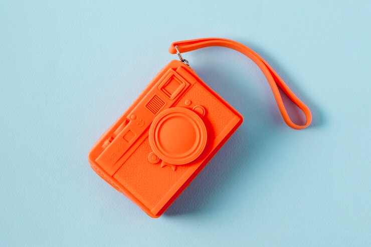 Free Photo an overhead view of an orange purse in camera shape on blue backdrop