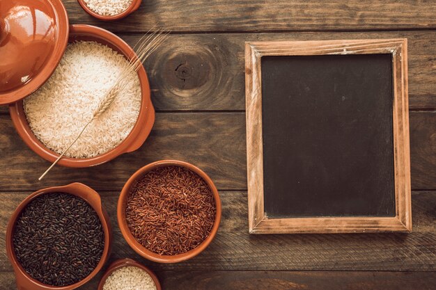 Overhead view of organic rice grains in bowl with blank blackboard