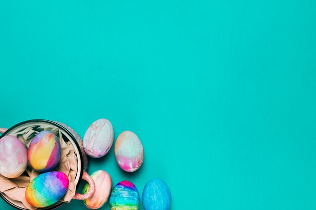 An overhead view of painted watercolor easter eggs on turquoise backdrop