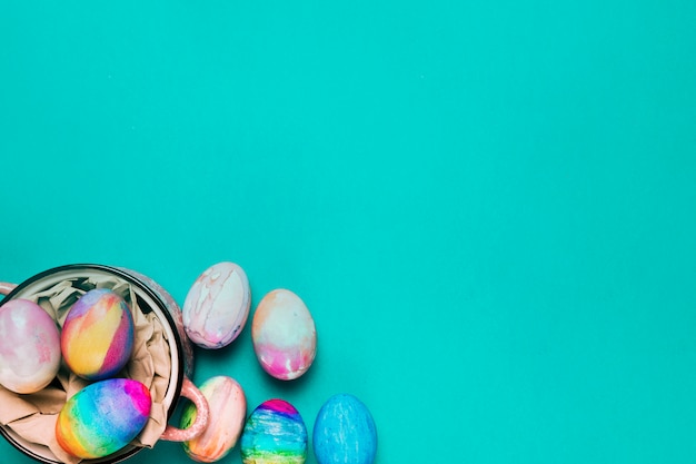 An overhead view of painted watercolor easter eggs on turquoise backdrop