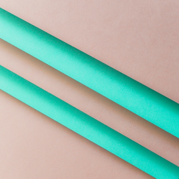 An overhead view of paper turquoise stripes over the brown backdrop