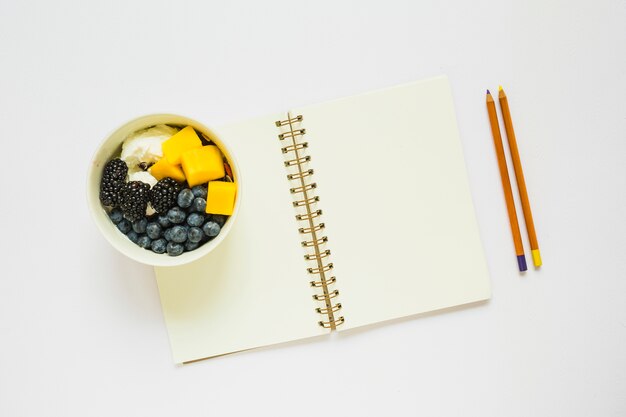 컵에 건강 과일과 연필과 빈 나선형 노트북의 오버 헤드보기