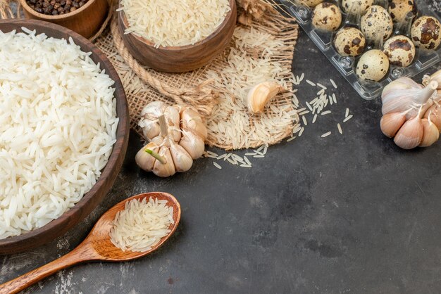 Overhead view of perfect long rice brown bowls on nude color towel eggs garlics peppers on dark table