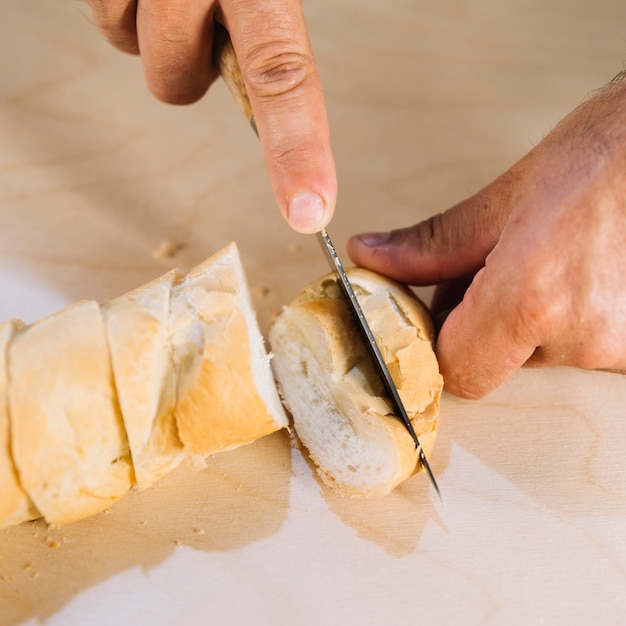 An overhead view of a person cutting bread with knife