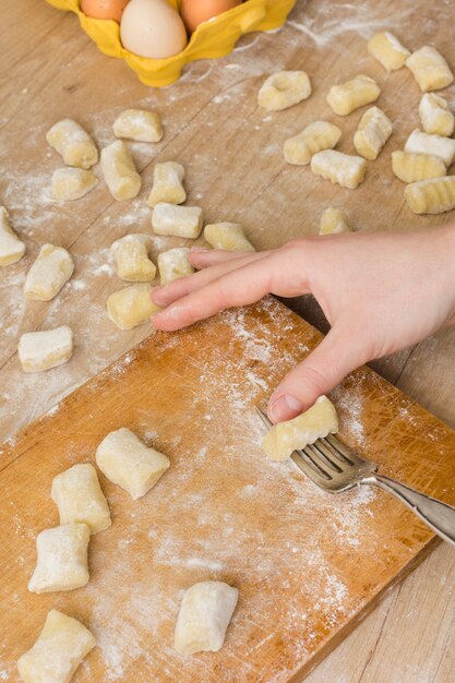 An overhead view of a person preparing the pasta gnocchi dough on chopping board