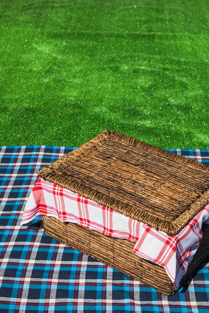 녹색 잔디 위에 체크 무늬 테이블에 피크닉 바구니의 오버 헤드보기