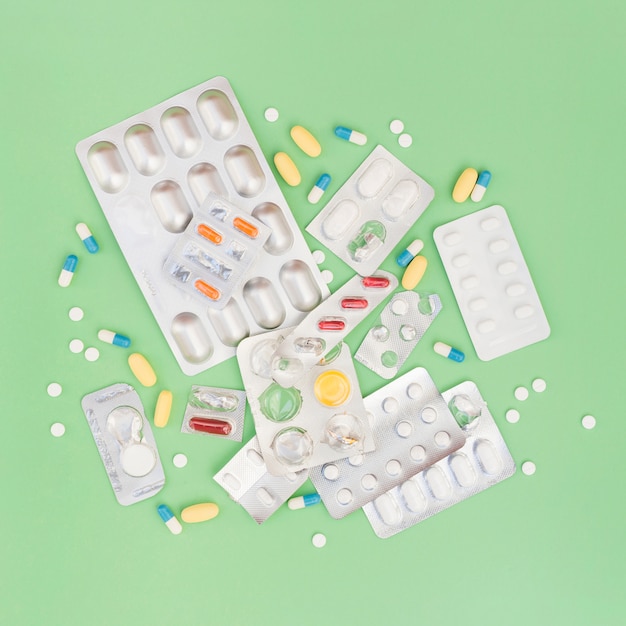 Free photo an overhead view of pills and blister pack on green background