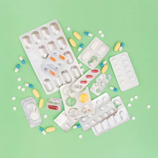 An overhead view of pills and blister pack on green background