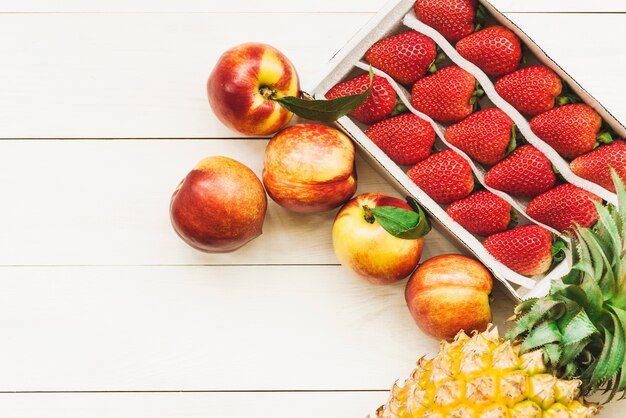 Overhead view of pineapple; apples and strawberries on wooden surface