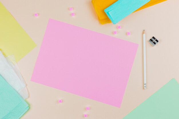 Вид сверху розовый чистый лист бумаги с карандашом и точилка на цветном фоне