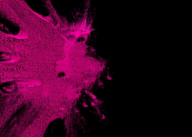 Overhead view of pink color powder explosion with copy space for text on black surface