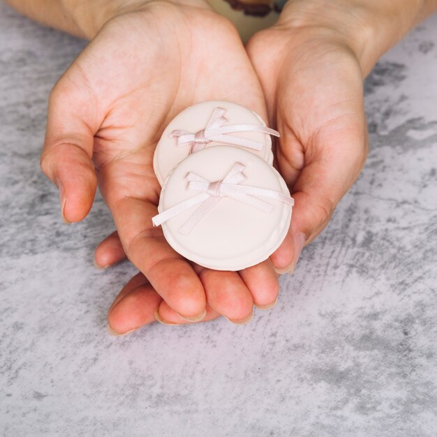 An overhead view of pink macaroons with bow in the hands