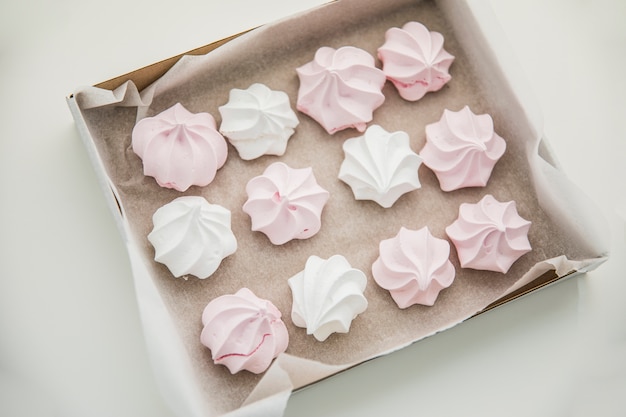 An overhead view of pink and white zephyrs in the box on white background