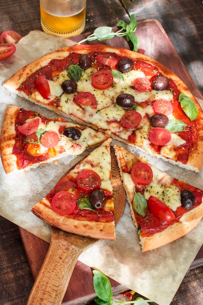 An overhead view of pizza slices on wooden chopping board