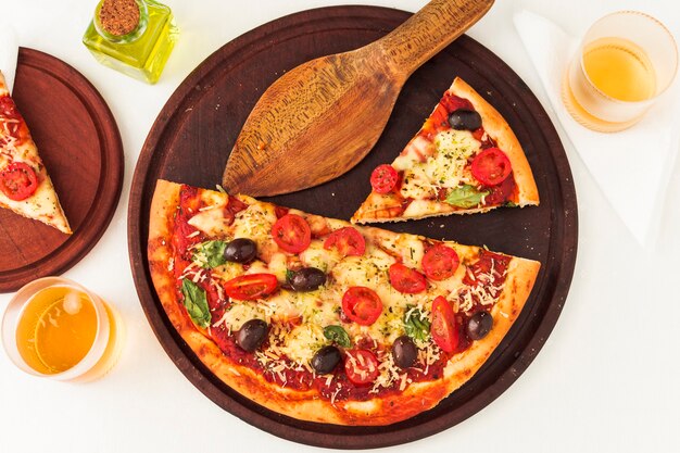 An overhead view of pizza on wooden board with spatula