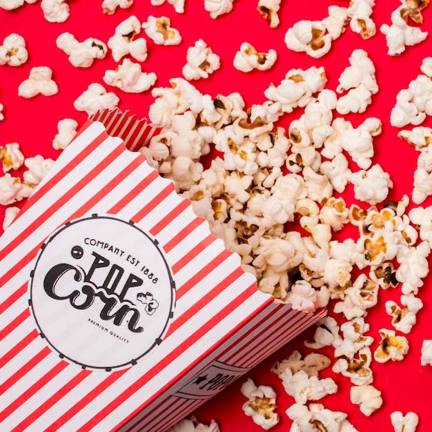 An overhead view of popcorns spilled on red backdrop