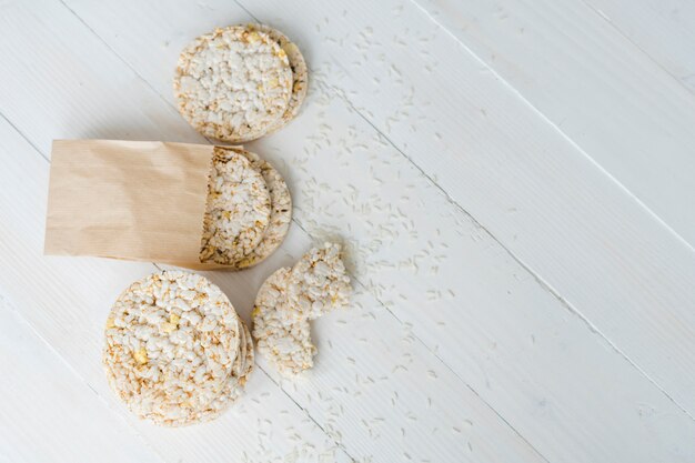 An overhead view of puffed rice with grains on white wooden desk