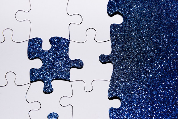 Overhead view of puzzle piece on blue glitter background