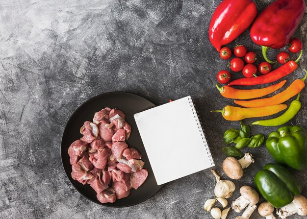 ノートパソコンとカラフルな野菜の生の肉の汚れた背景のオーバーヘッドビュー