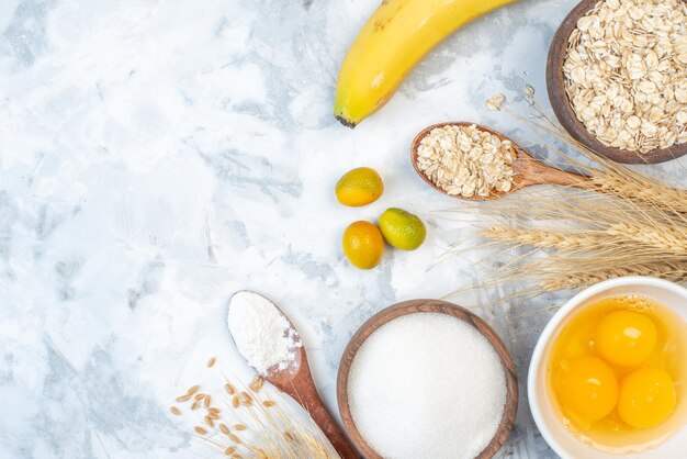 Overhead view of raw oatmeal kumquats spikes and sugar cracked eggs bananas on ice background