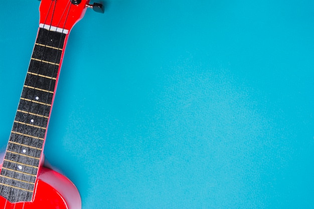 An overhead view of red acoustic classic guitar on blue backdrop
