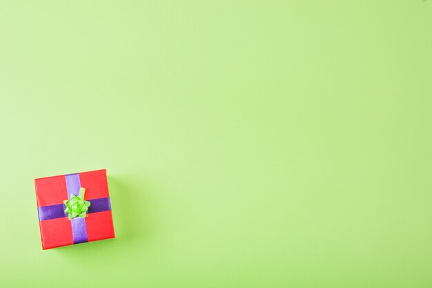 Overhead view of red box wrapped with decorative ribbon over the green background