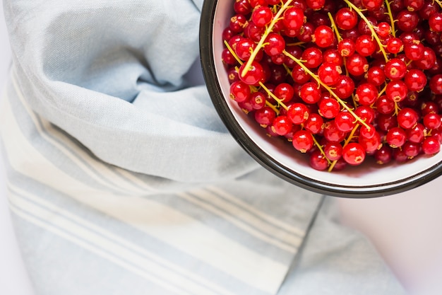 An overhead view of red currants twigs bowl and napkin