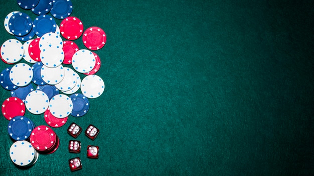 Overhead view of red dices and casino chips on green poker background