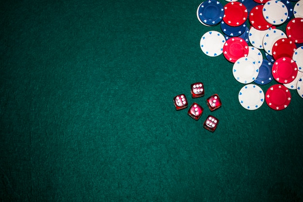 Overhead view of red dices and casino chips on green poker background