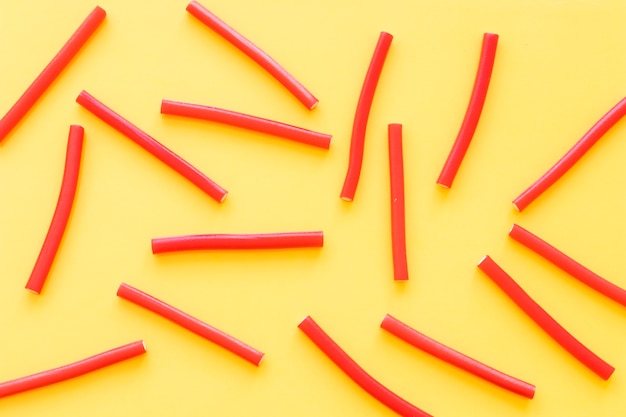 Overhead view of red licorice candies on yellow backdrop