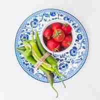 Foto gratuita una vista dall'alto di pomodori rossi e fascio di peperoncini verdi sul piatto in ceramica