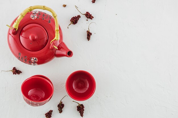 An overhead view of red traditional tea cup and teapot with herbs isolated on white background