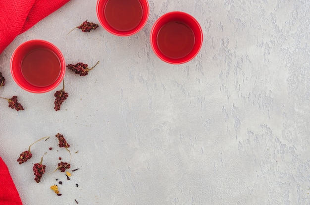 Free photo an overhead view of red traditional tea cup with herbs on grey textured backdrop