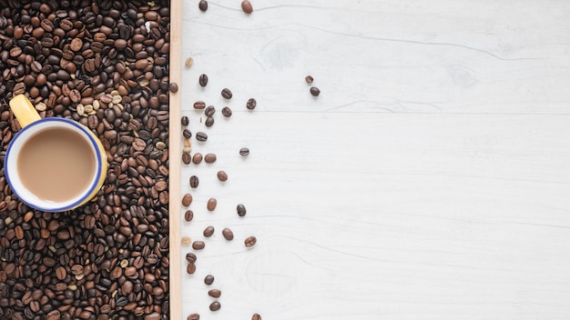 Free photo an overhead view of roasted coffee beans and coffee cup